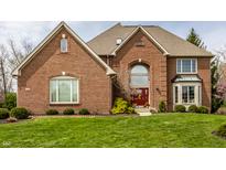 Stunning brick home featuring a red front door, well-manicured lawn, and mature landscaping at 7326 Elm Ridge Dr, Indianapolis, IN 46236