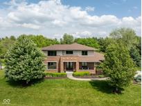 Aerial view of a two story brick home with mature landscaping, large front yard, and a charming walkway leading to the front door at 13225 Gatman Ct, Carmel, IN 46032