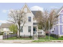Charming two-story home with a black metal fence and mature trees in full bloom at 2263 N Delaware St, Indianapolis, IN 46205