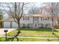 Charming two-story home with a well-maintained lawn, attached two-car garage, and a welcoming front entrance at 7624 Snowflake Dr, Indianapolis, IN 46227