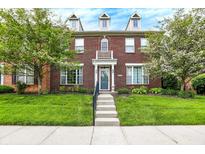 Inviting townhouse featuring a red brick facade, dormer windows, and well-maintained lawn at 13510 E 131St St, Fishers, IN 46037