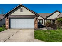 Charming home featuring a two-car garage, brick accents, complemented by lush green lawn and blue skies at 1720 Justin Ct, Indianapolis, IN 46219