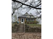 Charming home featuring brick accents, a quaint porch, and mature trees, perfect for a cozy living at 2657 E Riverside Dr, Indianapolis, IN 46208