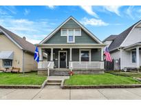 Charming home with a welcoming front porch, green lawn and beautifully maintained landscaping at 715 Cottage Ave, Indianapolis, IN 46203