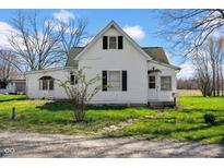 Charming white two-story home with dark shutters, a front yard, and a gravel driveway at 11015 S State Road 58, Columbus, IN 47201