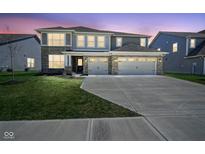 Beautiful home at dusk with a three-car garage, brick accents, and manicured front lawn at 2237 S Copperstone Dr, New Palestine, IN 46163