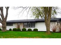 Charming single-story home featuring a painted brick exterior, complemented by dark accents and lush landscaping at 2416 Depauw Rd, Indianapolis, IN 46227