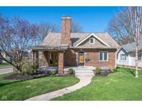Charming brick home featuring a welcoming front porch, lush lawn, and beautiful landscaping at 4102 N Illinois St, Indianapolis, IN 46208