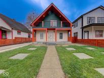 Striking two-story home featuring a modern design, a well-kept lawn, and a charming red-accented porch at 1360 N Dearborn St, Indianapolis, IN 46201