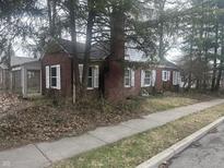 Charming single-story red brick home featuring white shutters and mature trees surrounding the property at 1701 Broad Ripple Ave, Indianapolis, IN 46220