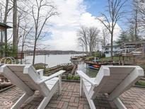 Inviting brick patio featuring two white Adirondack chairs overlooking a serene lake and private boat dock at 6599 Meadowlark Dr, Nineveh, IN 46164