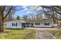 Charming single-story home featuring light blue siding, dark shutters, a fountain, and a paved driveway at 1707 W 76Th Pl, Indianapolis, IN 46260