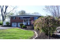 Charming two-story brick home with a well-manicured lawn, mature trees, and attached two car garage at 3790 E Pleasant Run Parkway North Dr, Indianapolis, IN 46201