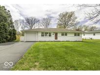 Charming single-story home with a well-manicured lawn and a paved driveway leading to an attached garage at 7144 Lockwood Ln, Indianapolis, IN 46217