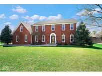 Charming two-story red brick home with a well-manicured lawn and mature trees at 7265 Derbyshire Dr, Cumberland, IN 46229