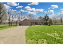 Inviting ranch home featuring a well-manicured lawn, long driveway, and an attached two-car garage at 7608 Andrew Turn, Plainfield, IN 46168