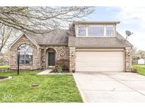 Charming brick home featuring a well-maintained lawn, arched entry, and attached two-car garage at 7715 High View Cir, Indianapolis, IN 46236