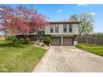 Charming two-story home featuring a well-maintained lawn, mature tree, and an attached two-car garage at 8235 Picadilly Ln, Indianapolis, IN 46256