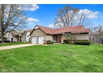 Charming home featuring an attached two-car garage, a neatly manicured green lawn, and mature trees at 1829 Catalano Dr, Indianapolis, IN 46214