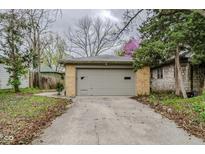 This is a detached garage with a concrete driveway surrounded by trees and foliage at 5017 E 14Th St, Indianapolis, IN 46201
