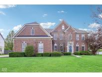 Charming two-story brick home with manicured lawn and lush landscaping under a bright blue sky at 4281 Honeysuckle Ln, Zionsville, IN 46077