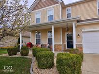 Inviting two-story home featuring a charming front porch, lush landscaping, and a well-maintained lawn at 4383 Round Lake Bnd, Indianapolis, IN 46234