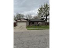 Charming single-story home featuring stone accents, a two-car garage, and a well-maintained front yard at 613 Rahkewood Dr, Indianapolis, IN 46217