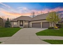 Beautiful brick home featuring a three-car garage, manicured lawn, and gorgeous landscaping at sunset at 6841 W Glory Maple Dr, McCordsville, IN 46055