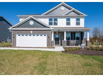 Two-story home featuring a brick facade, attached two car garage, and covered porch with rocking chairs at 7628 Big Bend Blvd, Camby, IN 46113