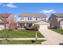 Charming two-story home boasts a manicured lawn, covered porch and attached two-car garage at 19546 Forsythe Dr, Noblesville, IN 46060
