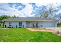 Charming one-story home with blue siding, well-manicured lawn, and a welcoming front porch with rocking chairs at 20892 Overdorf Rd, Noblesville, IN 46062