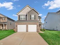 Two-story home featuring a two-car garage, brick accents, and a well-maintained lawn at 3053 Creekridge Ct, Columbus, IN 47201