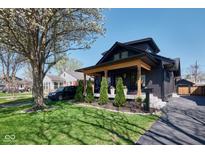 Beautifully landscaped front yard featuring a charming covered porch on a dark colored home at 6173 Rosslyn Ave, Indianapolis, IN 46220