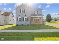 Charming two-story home featuring a inviting front porch, lush lawn and star decoration at 13 N Main St, Brooklyn, IN 46111