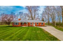 Charming red brick ranch home with a lush green lawn and mature trees at 1911 N Rangeline Rd, Anderson, IN 46012