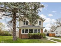 Charming two-story home with a brick foundation and a lovely front yard featuring a mature tree at 310 W 43Rd St, Indianapolis, IN 46208
