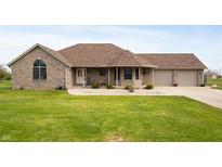 Charming brick home featuring an attached three car garage and a well-manicured front lawn at 3300 E Indian Hill Dr, Muncie, IN 47302