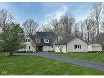 Traditional home showcasing a long driveway, lush lawn, and gray siding, complemented by dark shutters and a black roof at 4560 S 975 E, Zionsville, IN 46077