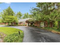 Charming single-story brick home features a circular driveway and mature trees at 8535 Washington Blvd, Indianapolis, IN 46240