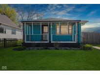 Charming, light-blue, one story home with a covered porch and freshly cut lawn at 1857 Calvin St, Indianapolis, IN 46203