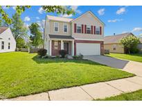 Charming two-story home featuring a well-manicured lawn, red shutters, and a two-car garage at 18904 Planer Dr, Noblesville, IN 46062