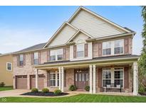Charming two-story brick home boasting a covered porch, manicured lawn, and an attached two-car garage at 4411 Westminster Pl, Columbus, IN 47201