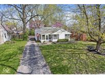 Charming cottage-style home featuring a well-manicured lawn, quaint walkway, and an American flag on the front porch at 6153 Evanston Ave, Indianapolis, IN 46220