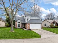 Charming two-story home with brick accents, attached garage, and well-manicured lawn and mature trees at 7775 Hollow Ridge Cir, Indianapolis, IN 46256