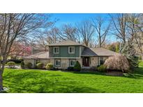 Charming two-story home with stone accents, mature trees, and a lush green lawn at 13892 Adios Pass, Carmel, IN 46032