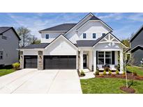 Charming two-story home with a three-car garage and a welcoming front porch seating area at 15341 Montfort Dr, Noblesville, IN 46062