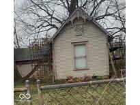 Charming small home with architectural details needing restoration, set behind a chain-link fence at 324 E Burgess Ave, Indianapolis, IN 46219