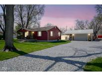 Charming red home features a gravel driveway leading to a detached garage at 502 N Maple St, Ingalls, IN 46048