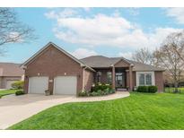 Charming brick home featuring a well-manicured lawn, a two-car garage, and beautiful landscaping at 6081 Boulder Ct, Columbus, IN 47201