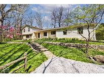 Charming home featuring stone retaining walls, lush lawn, and a winding gravel driveway at 6454 Dean Rd, Indianapolis, IN 46220